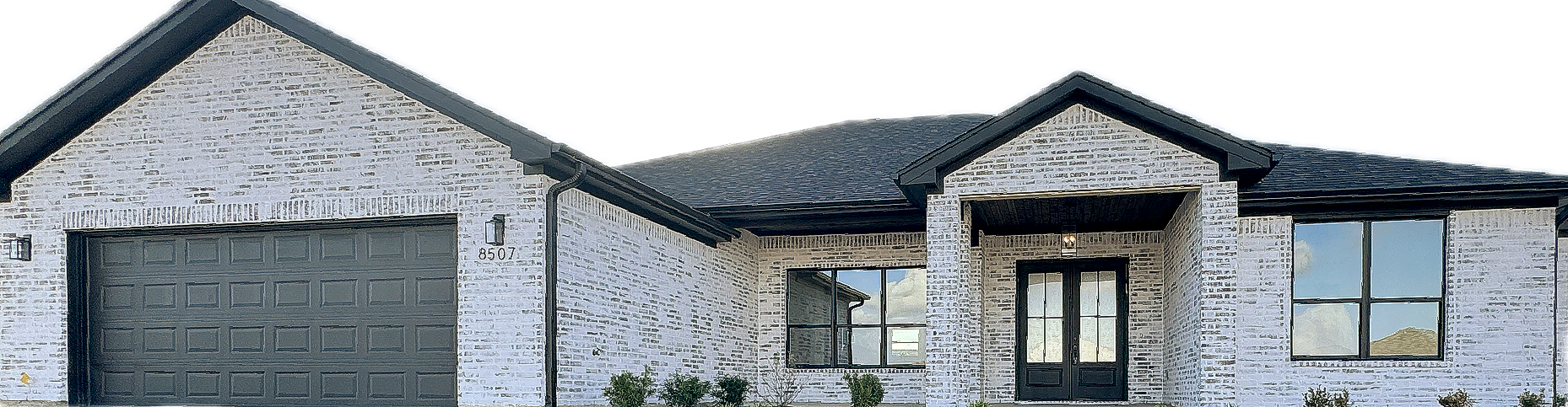 A house with light-colored stone, dark roof, and garage door; windows, and a front door.