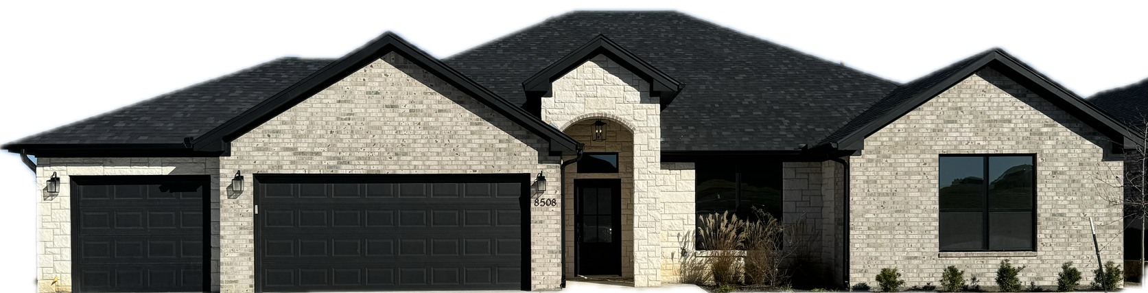 A light brick house with a dark roof and black garage doors.