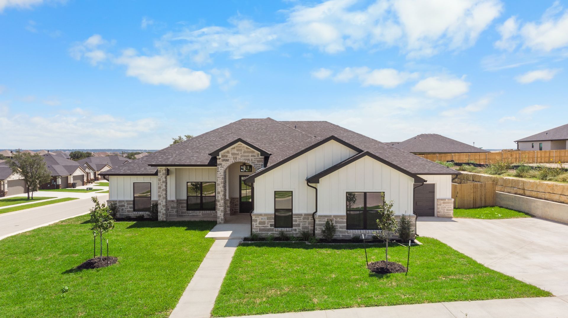 Brick and white house with attached garage and dry brown grass yard.
