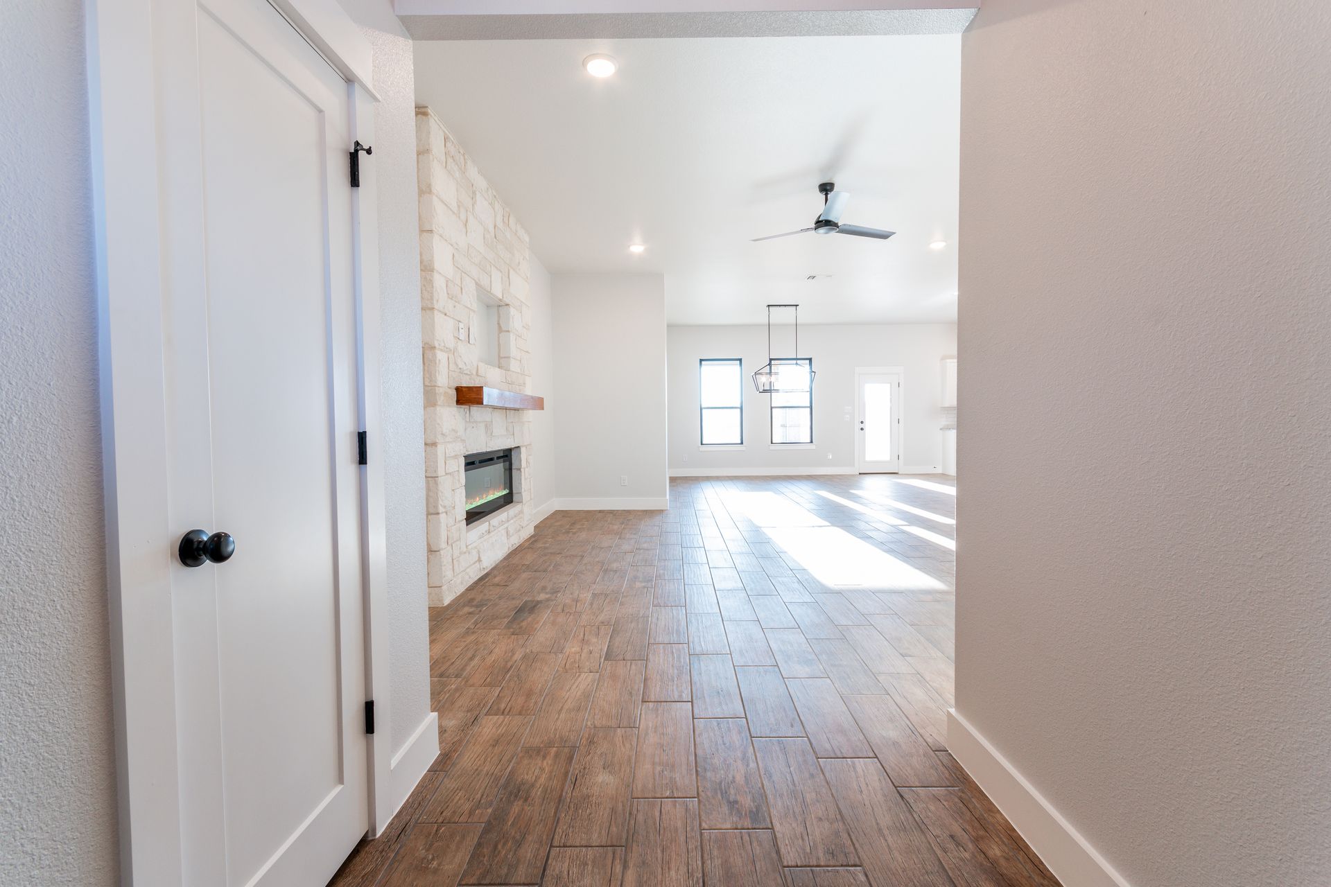Hallway with wood floors, white walls, and a fireplace with a white stone wall.