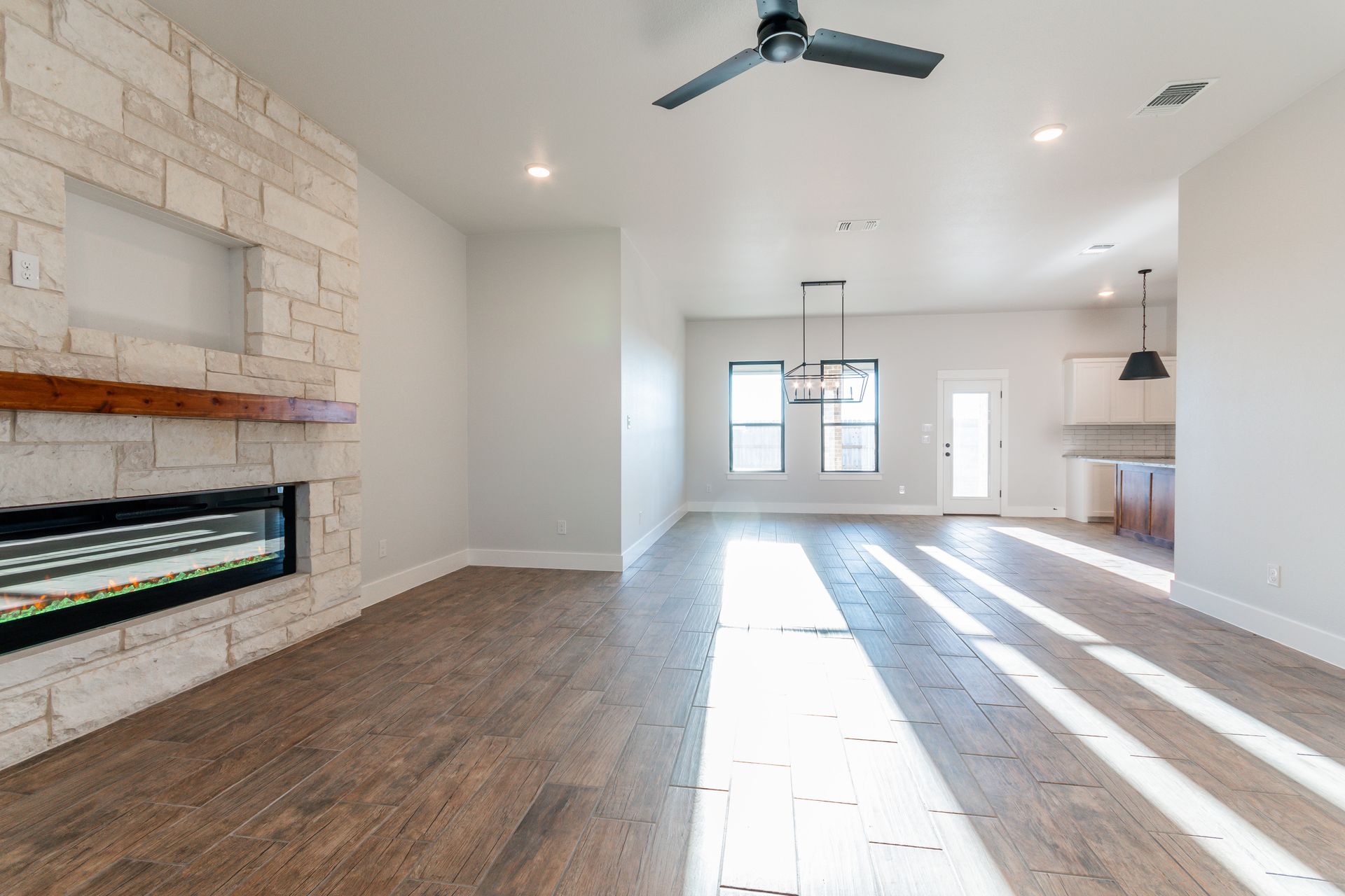 Spacious living room with a fireplace, hardwood floors, and a view into the kitchen area.