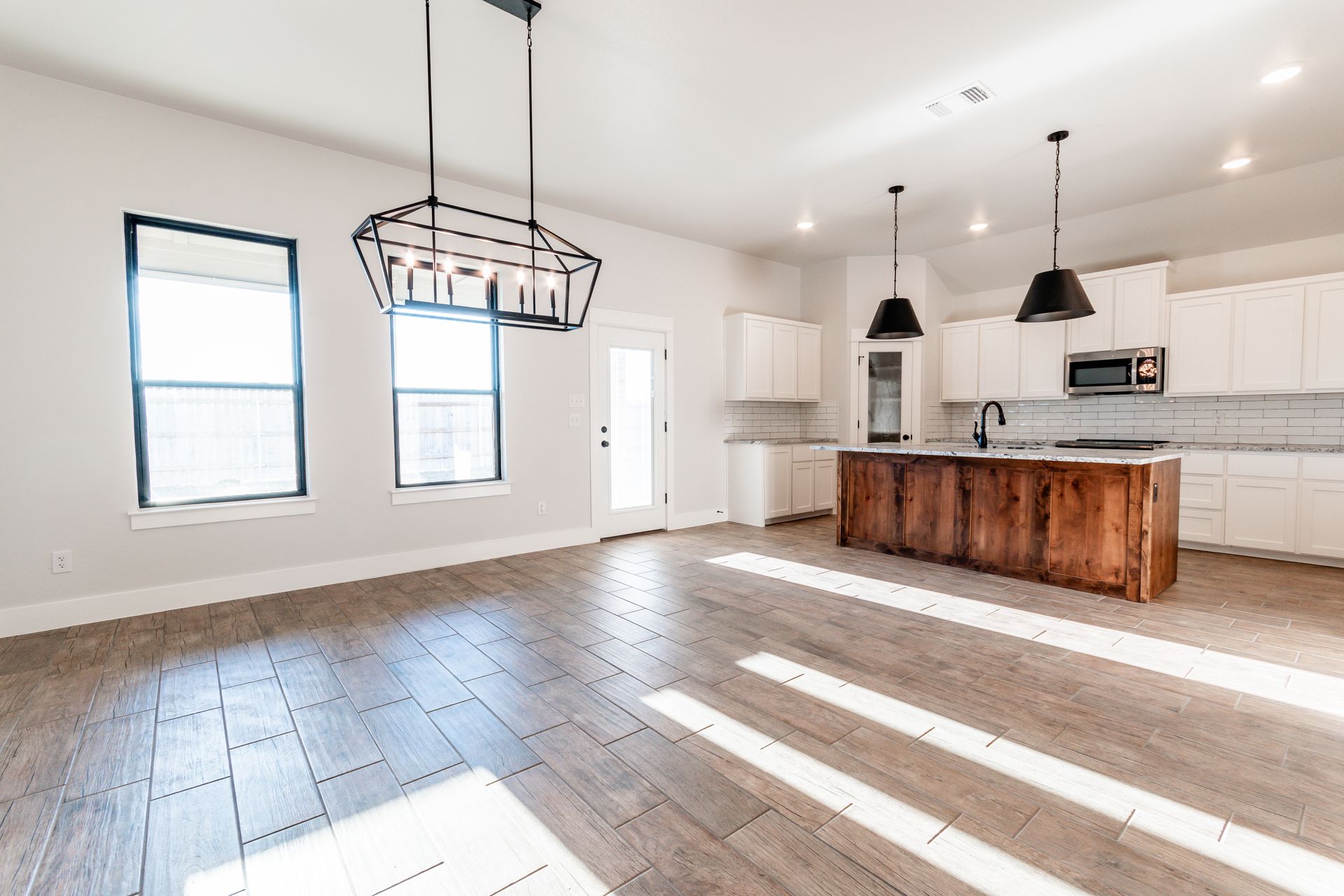 Open-concept kitchen and living area with hardwood floors, white cabinets, and a wooden island.