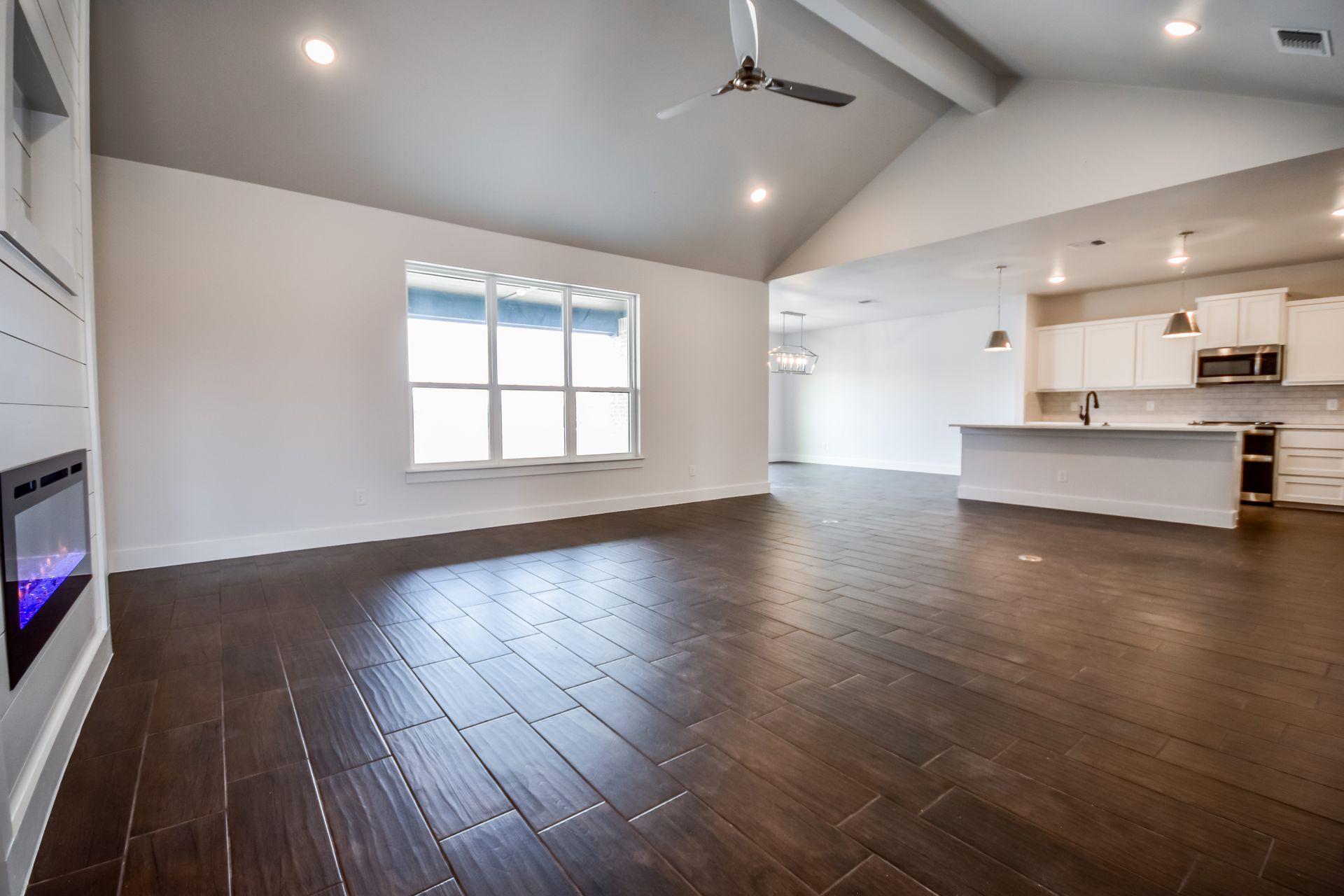 Spacious, open-plan living area with dark wood floors, white walls, and a modern kitchen.