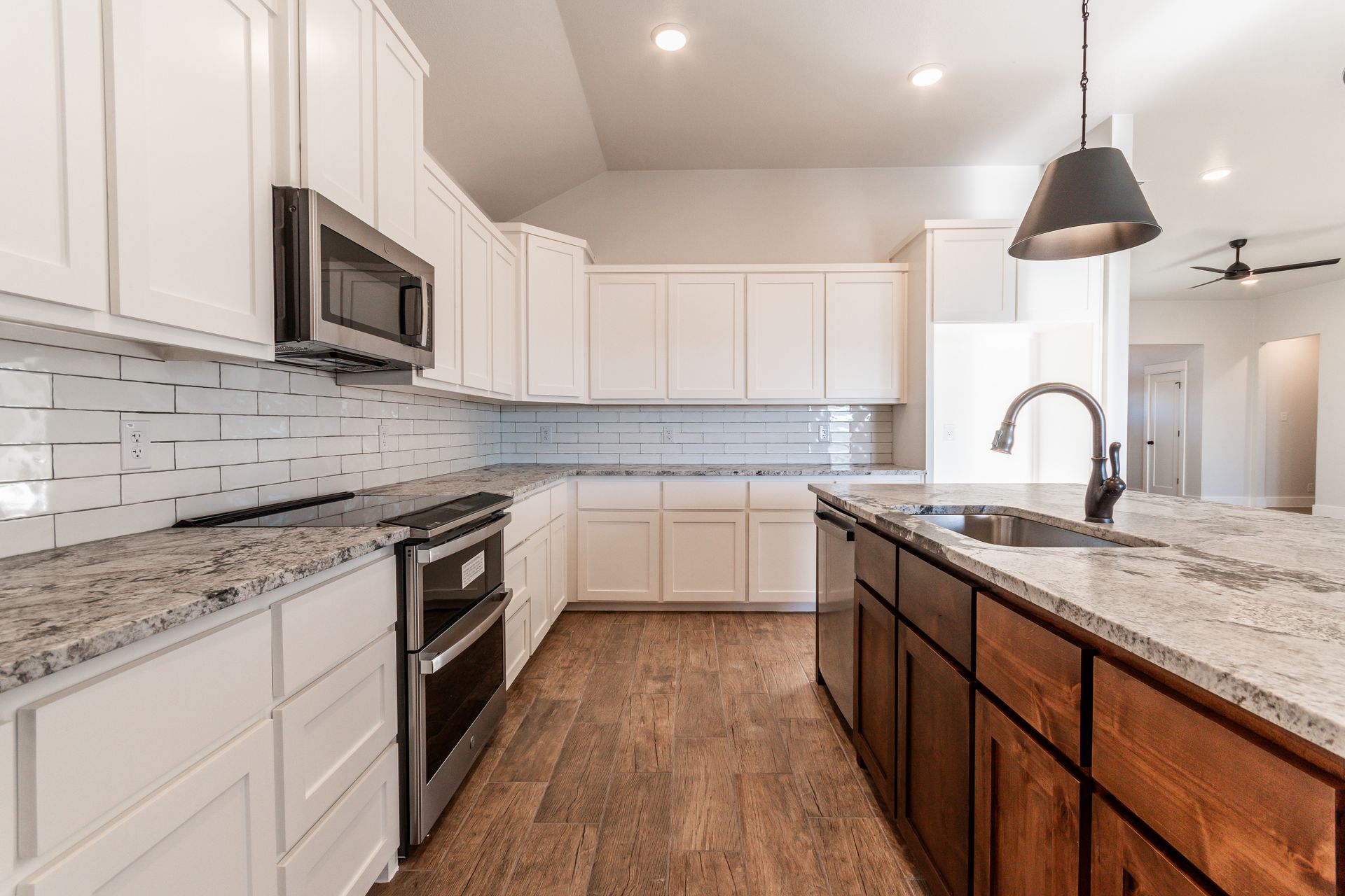 Modern kitchen with white cabinets, granite countertops, and a dark island.