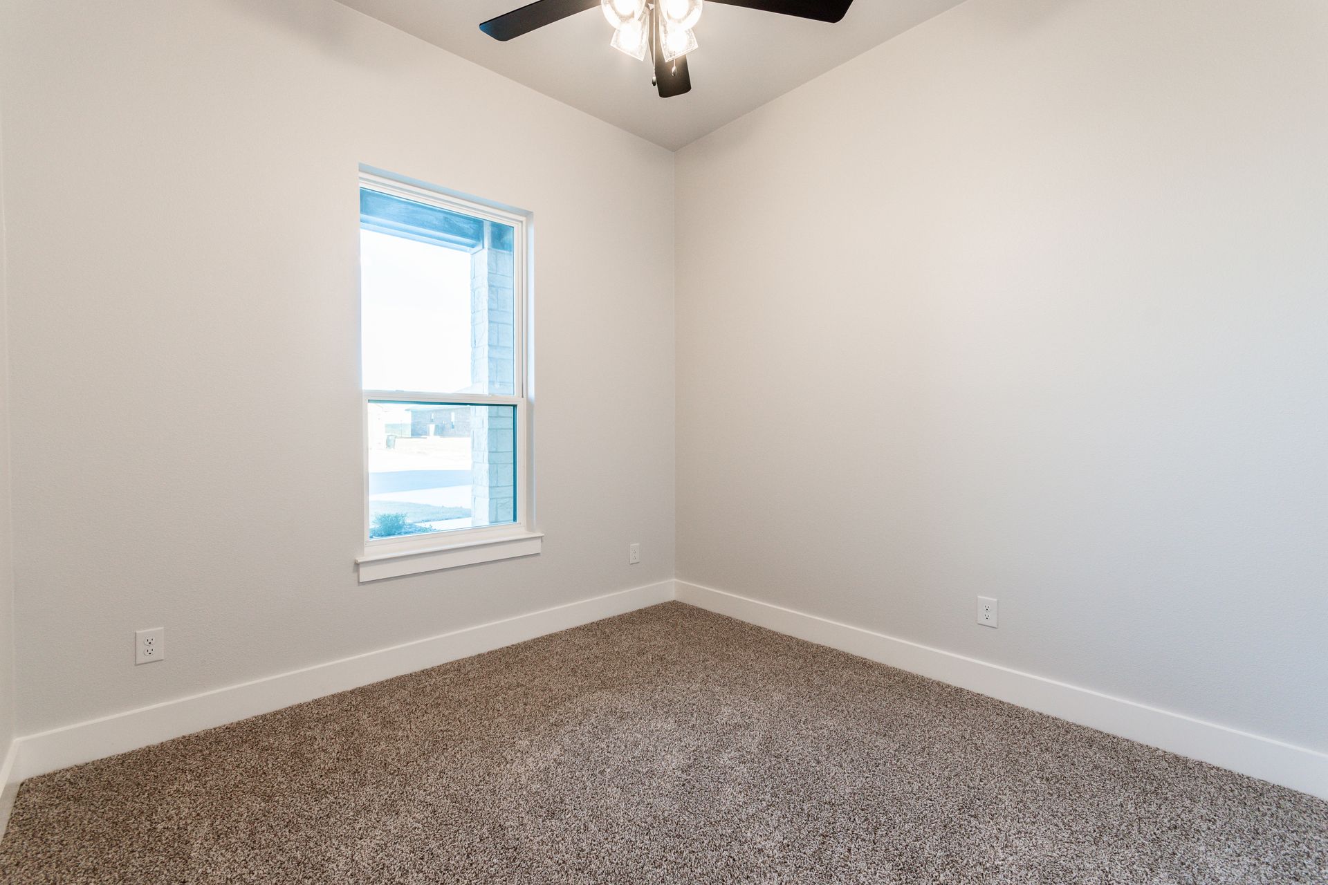 Empty bedroom with light walls, window, carpet, and ceiling fan.