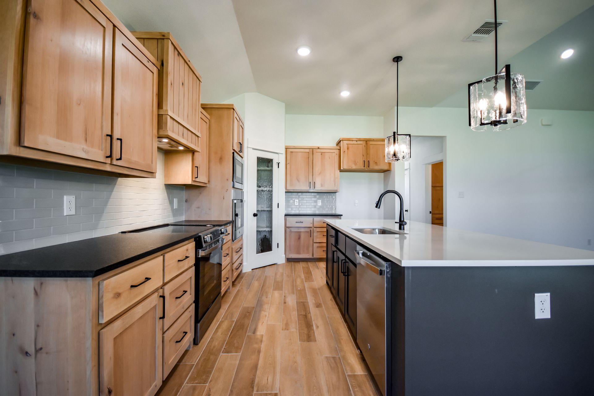 Kitchen with light wood cabinets, dark countertops, and a gray island.