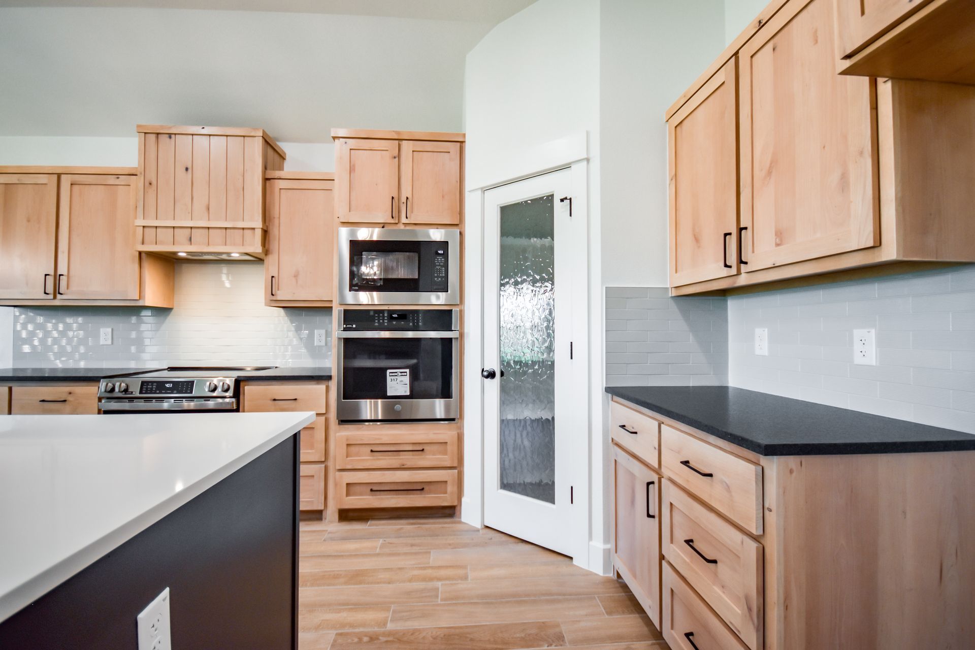 Kitchen with light wood cabinets, stainless steel appliances, and a pantry with a frosted glass door.