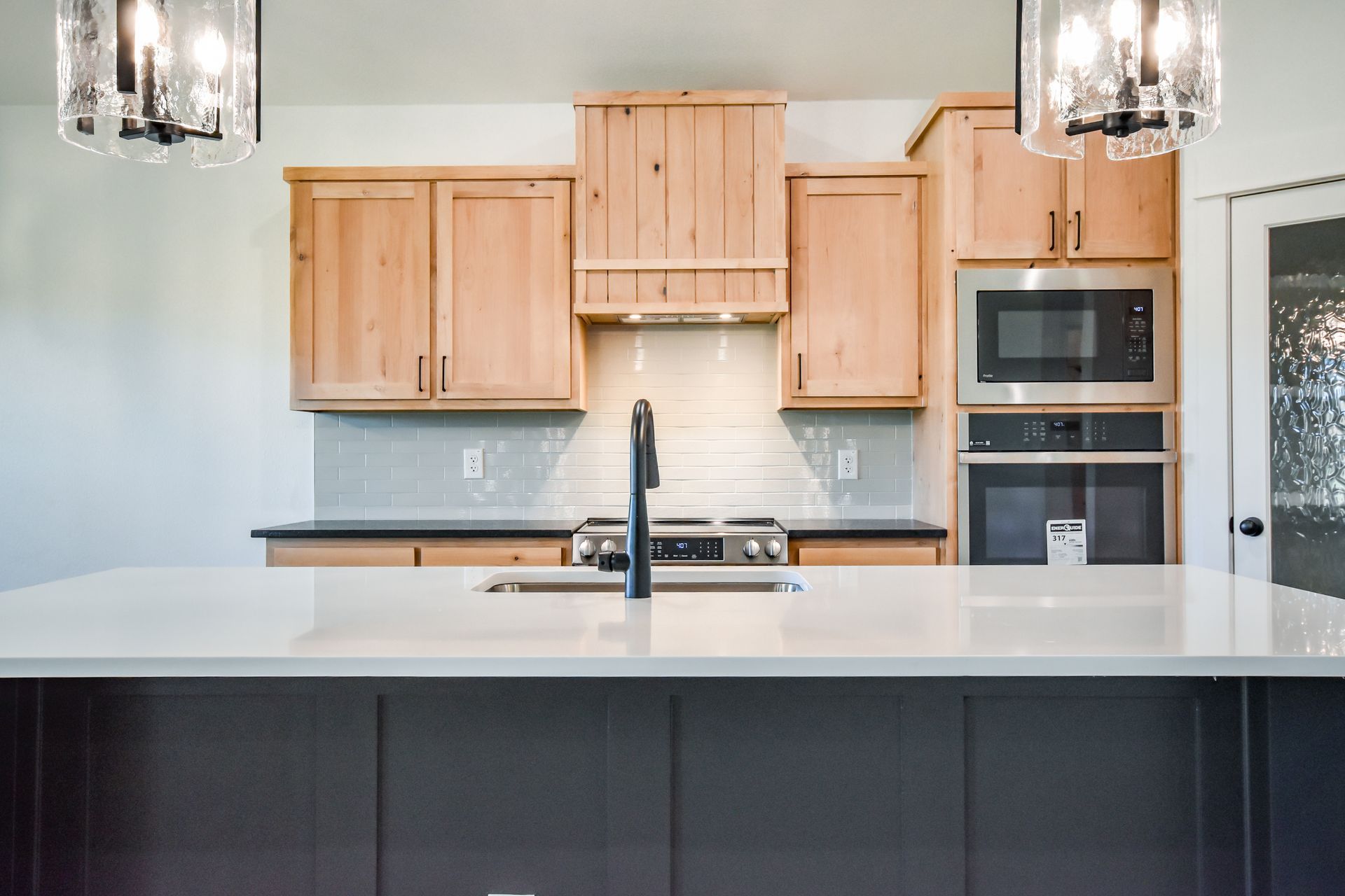 Modern kitchen with island, light wood cabinets, and stainless steel appliances.