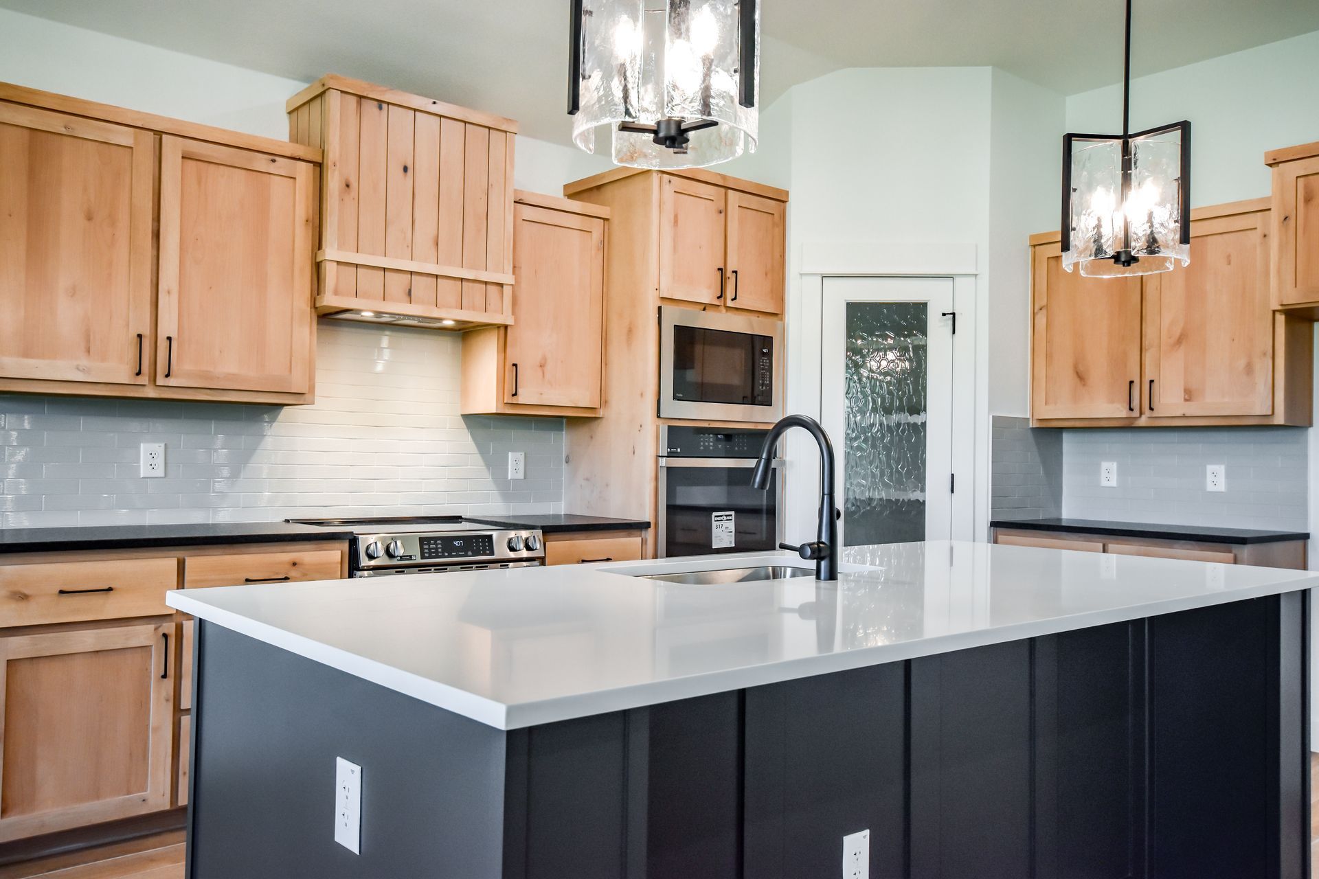 Kitchen with light wood cabinets, dark island, and white countertops.