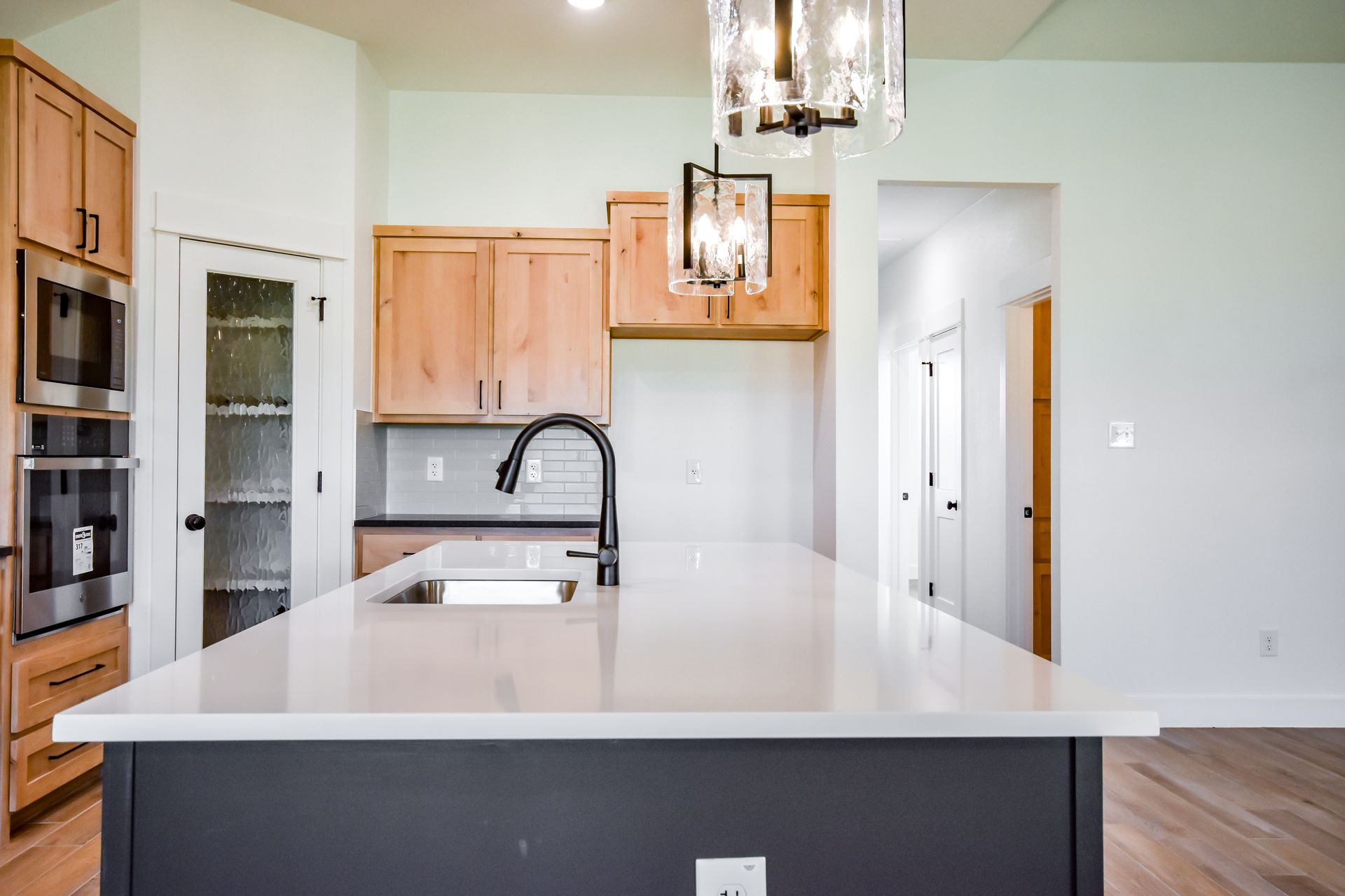 Modern kitchen with a gray island, light wood cabinets, and white countertops.