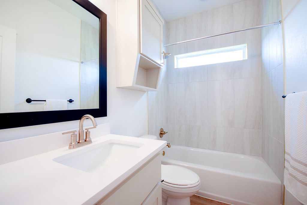 White bathroom with a sink, toilet, tub, and medicine cabinet.