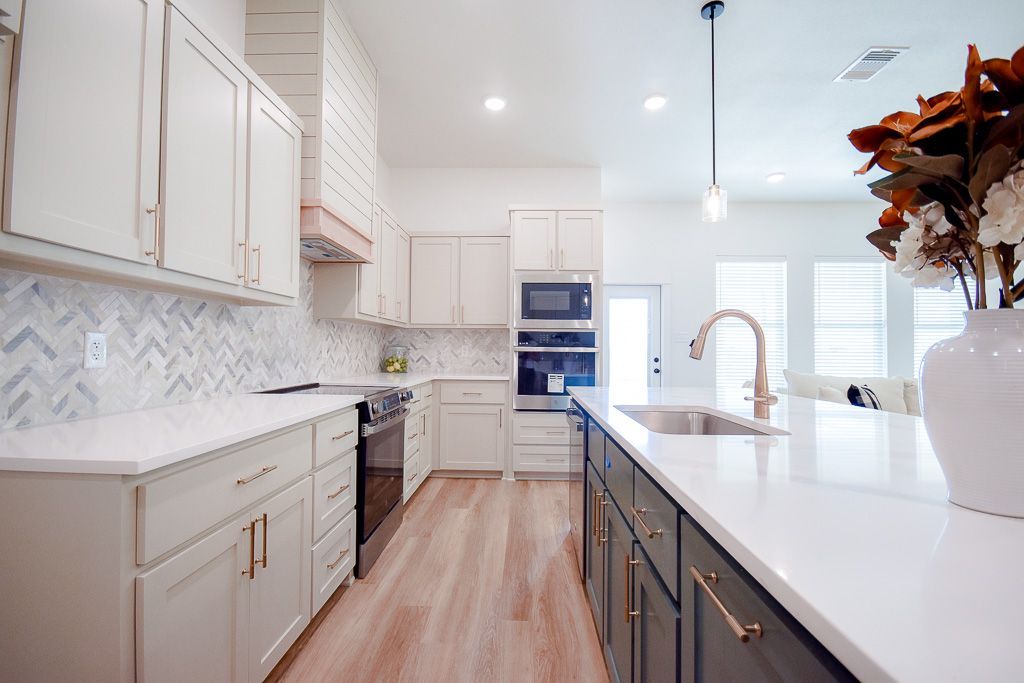Modern kitchen with white cabinets, dark island, and light wood flooring.