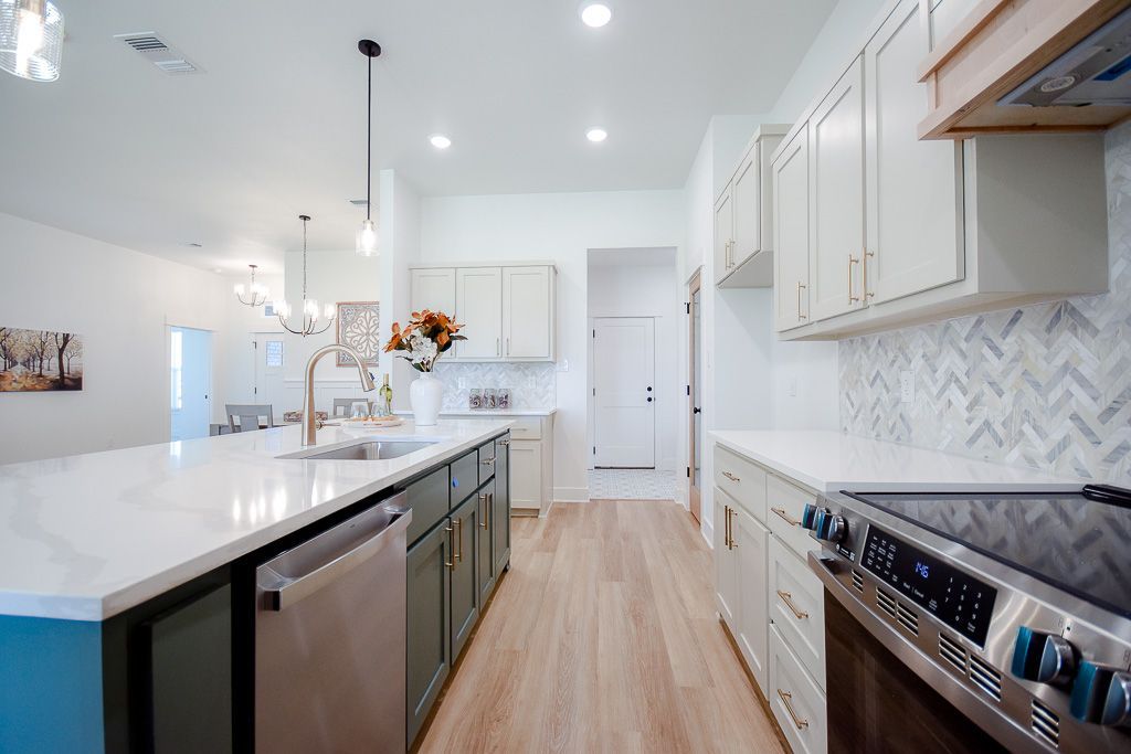 Modern kitchen with green island, white cabinets, and wood flooring.