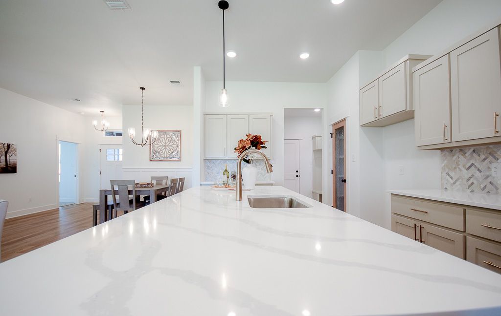 Bright kitchen with white countertops and cabinets, dining area visible in the distance.