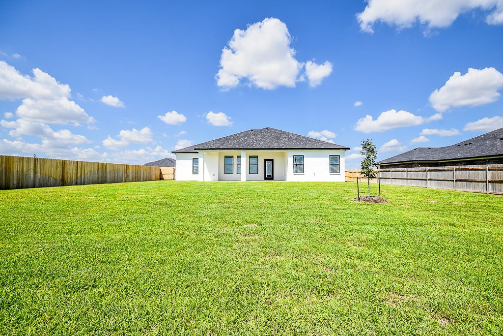 White house with dark roof and green lawn against a blue sky with clouds.