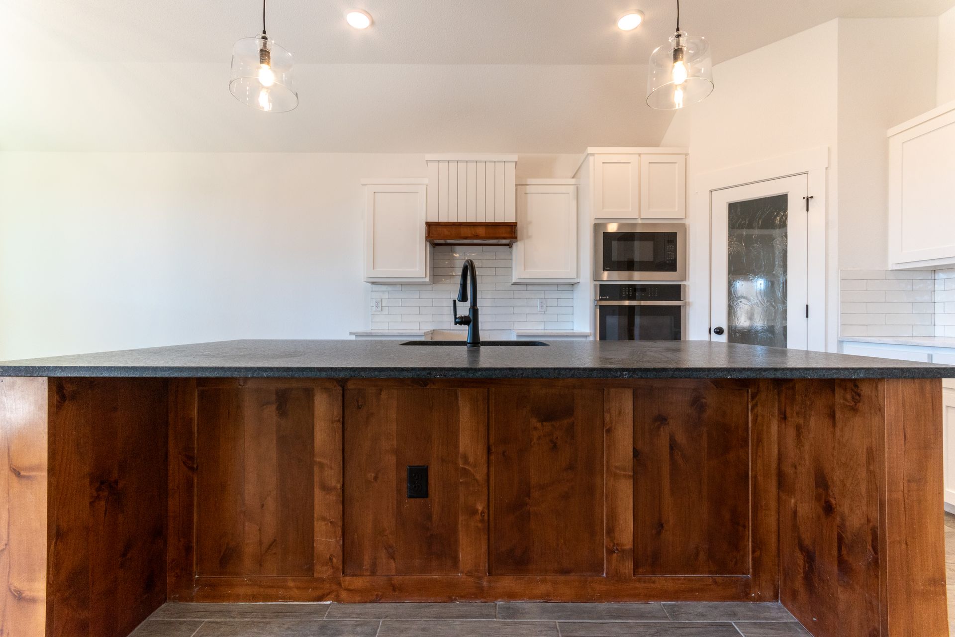 Kitchen with dark wood island, black countertop, white cabinets, and stainless steel appliances.