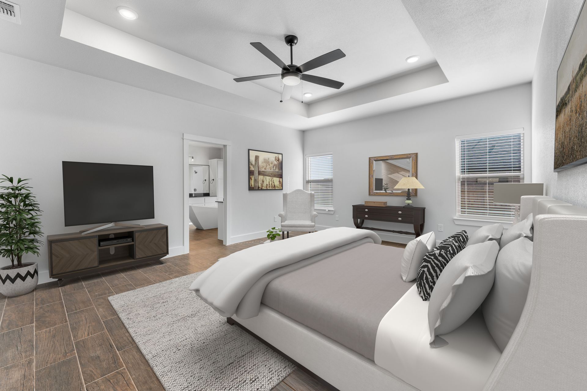 Bedroom with bed, TV, ceiling fan, and access to a bathroom. Neutral color palette and wood flooring.