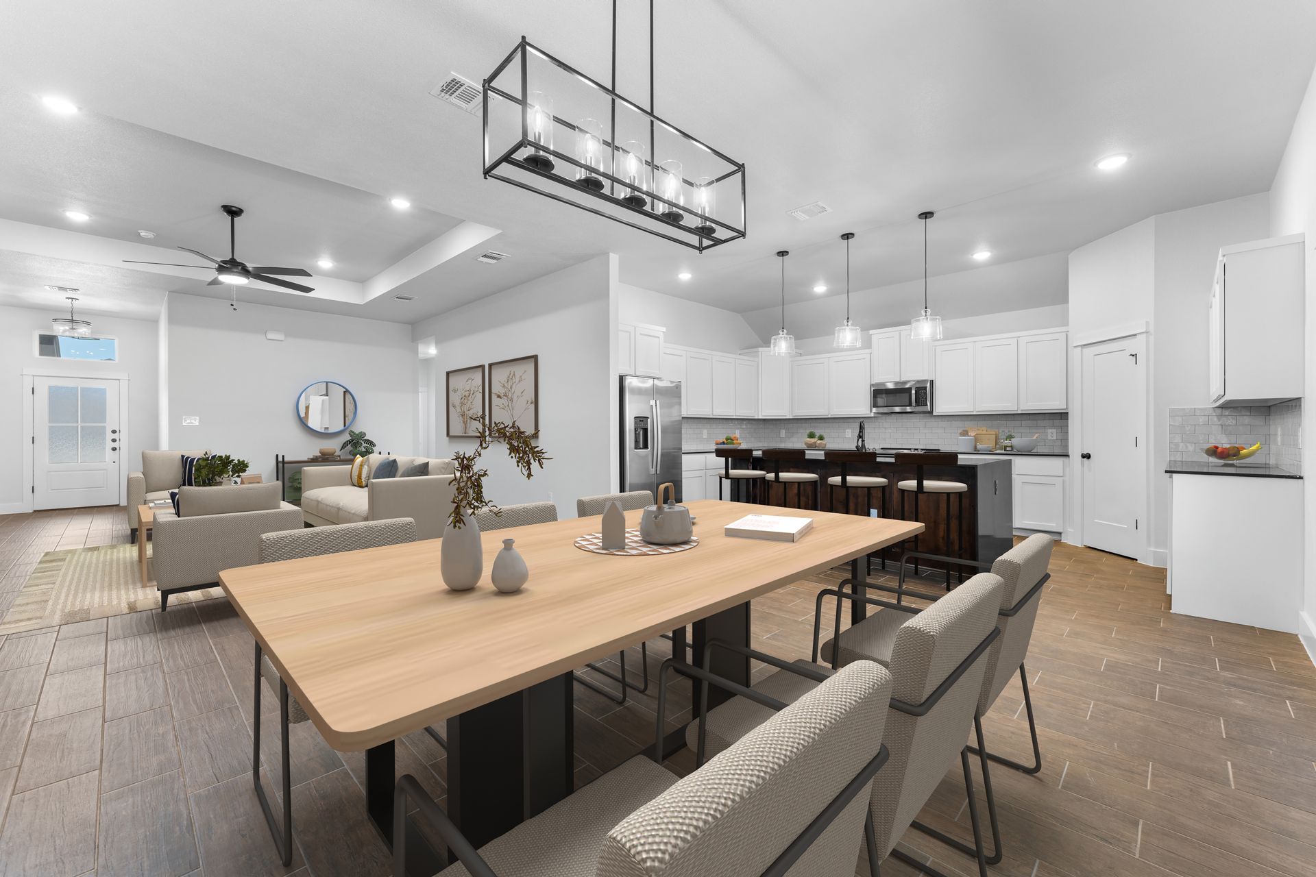 Open-concept living space with dining area, kitchen, and living room; light wood floors, white walls, and contemporary furnishings.
