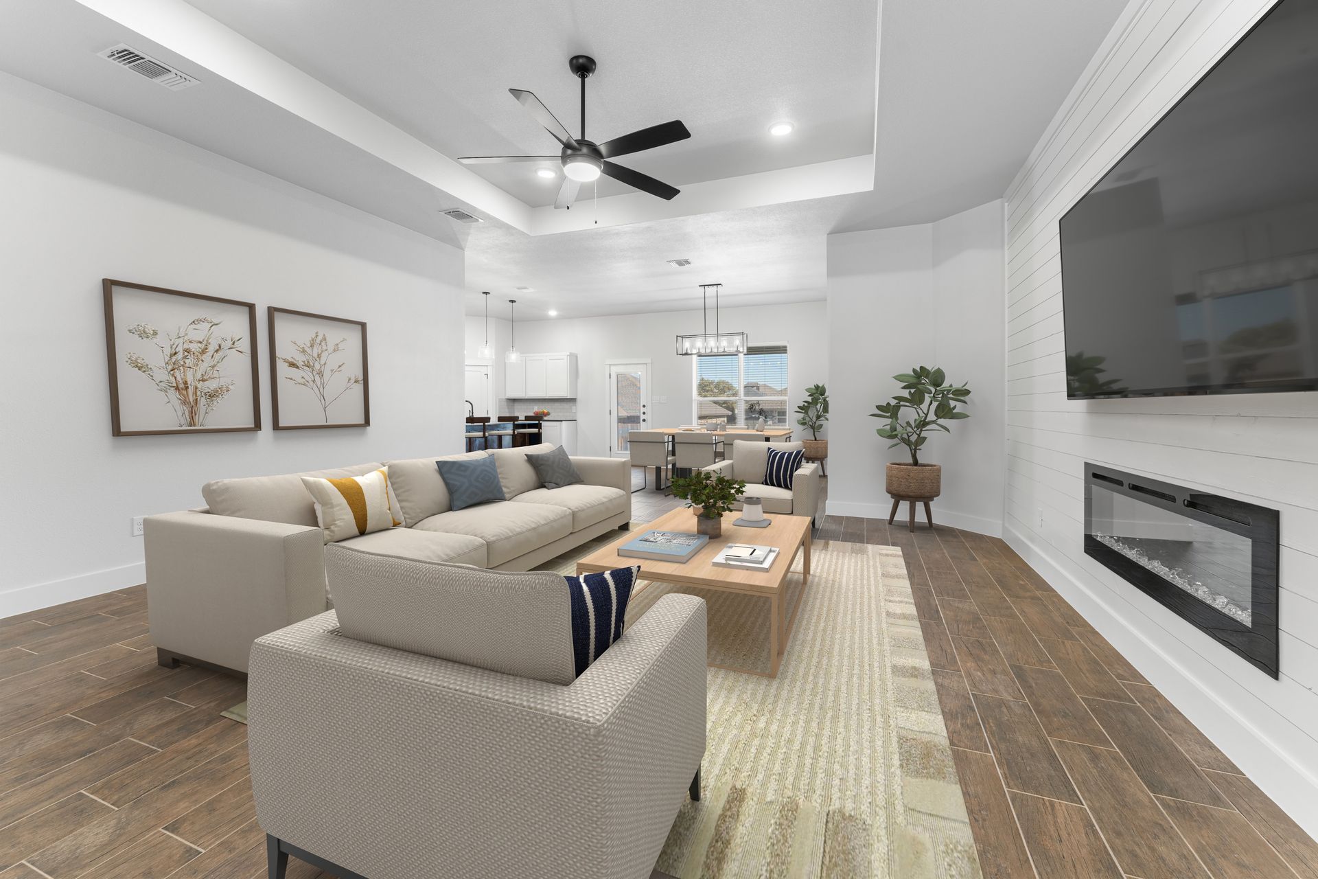 Living room with light-colored sofa, fireplace, TV, and open view to kitchen and dining area.
