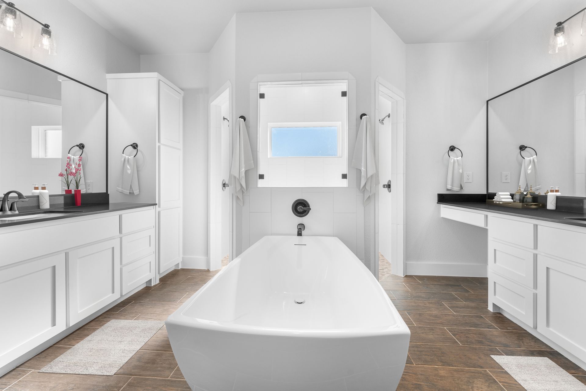 Bright white bathroom with a long soaking tub, two vanities, and a window.
