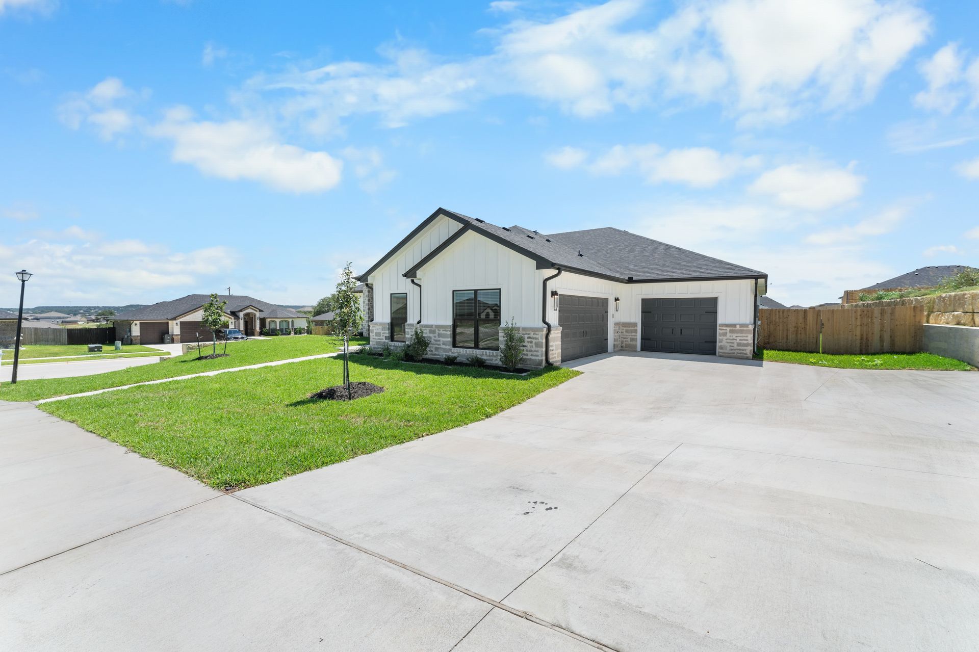 A modern, white house with a two-car garage, on a sunny day with a blue sky.