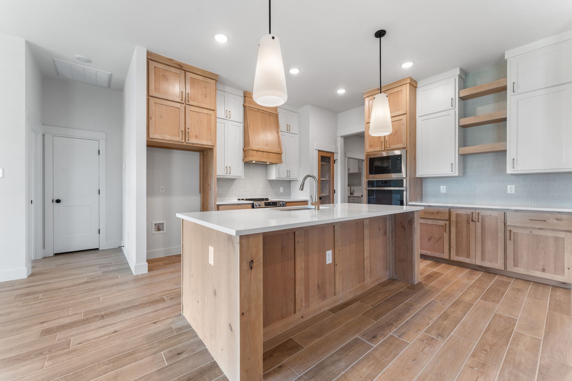 Modern kitchen with light wood cabinetry, white countertops, and an island.