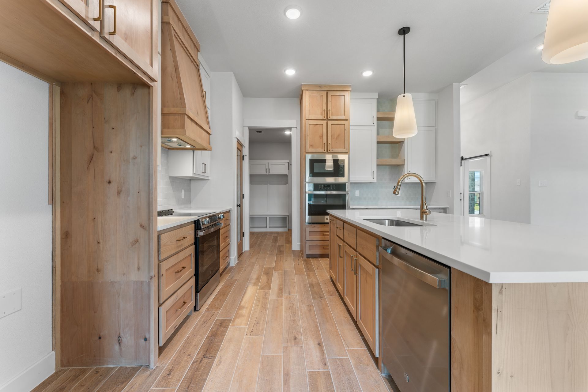Modern kitchen with light wood cabinets, stainless steel appliances, and white countertops.