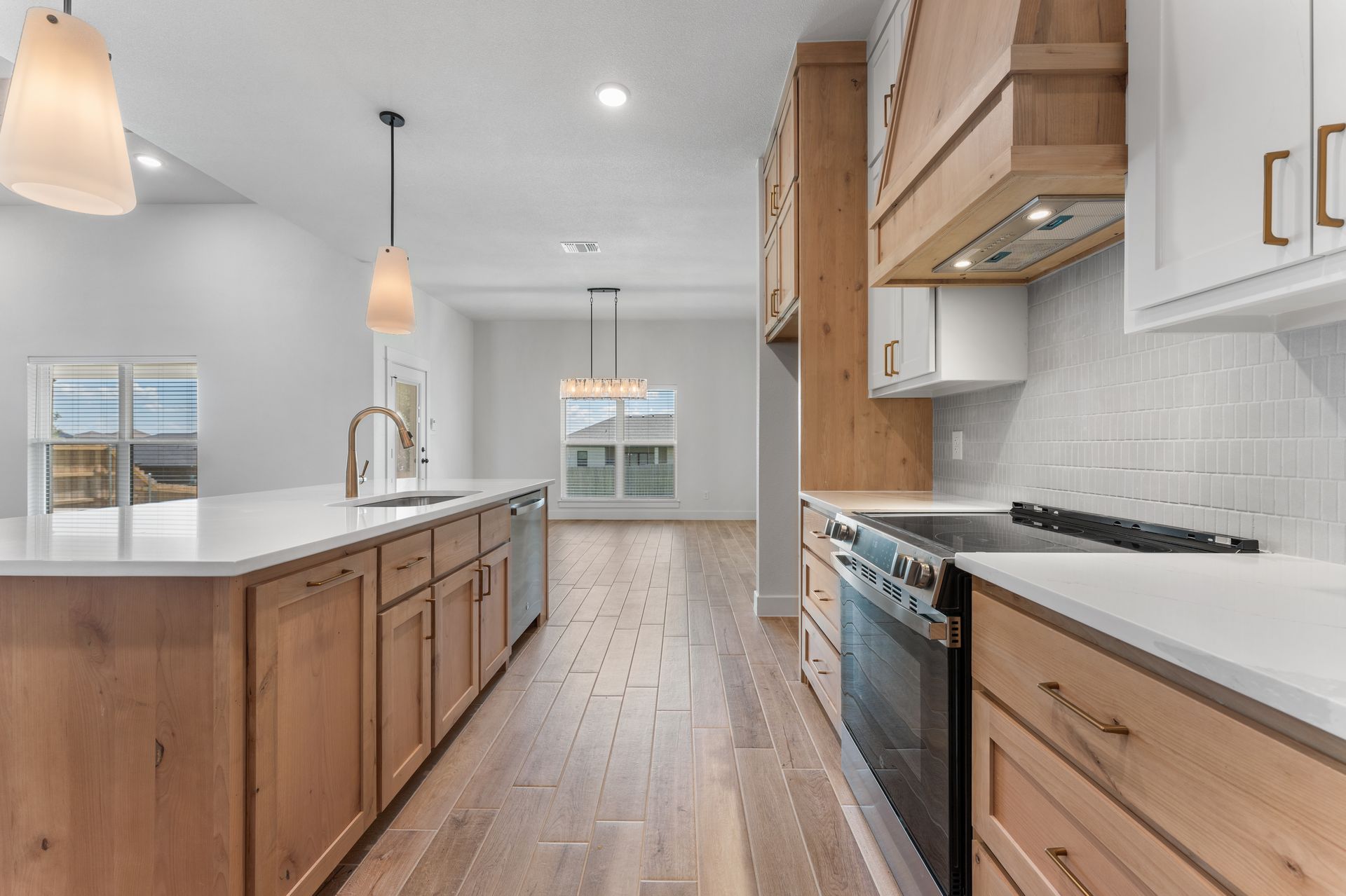 Modern kitchen with light wood cabinets, white countertops, and stainless steel appliances.