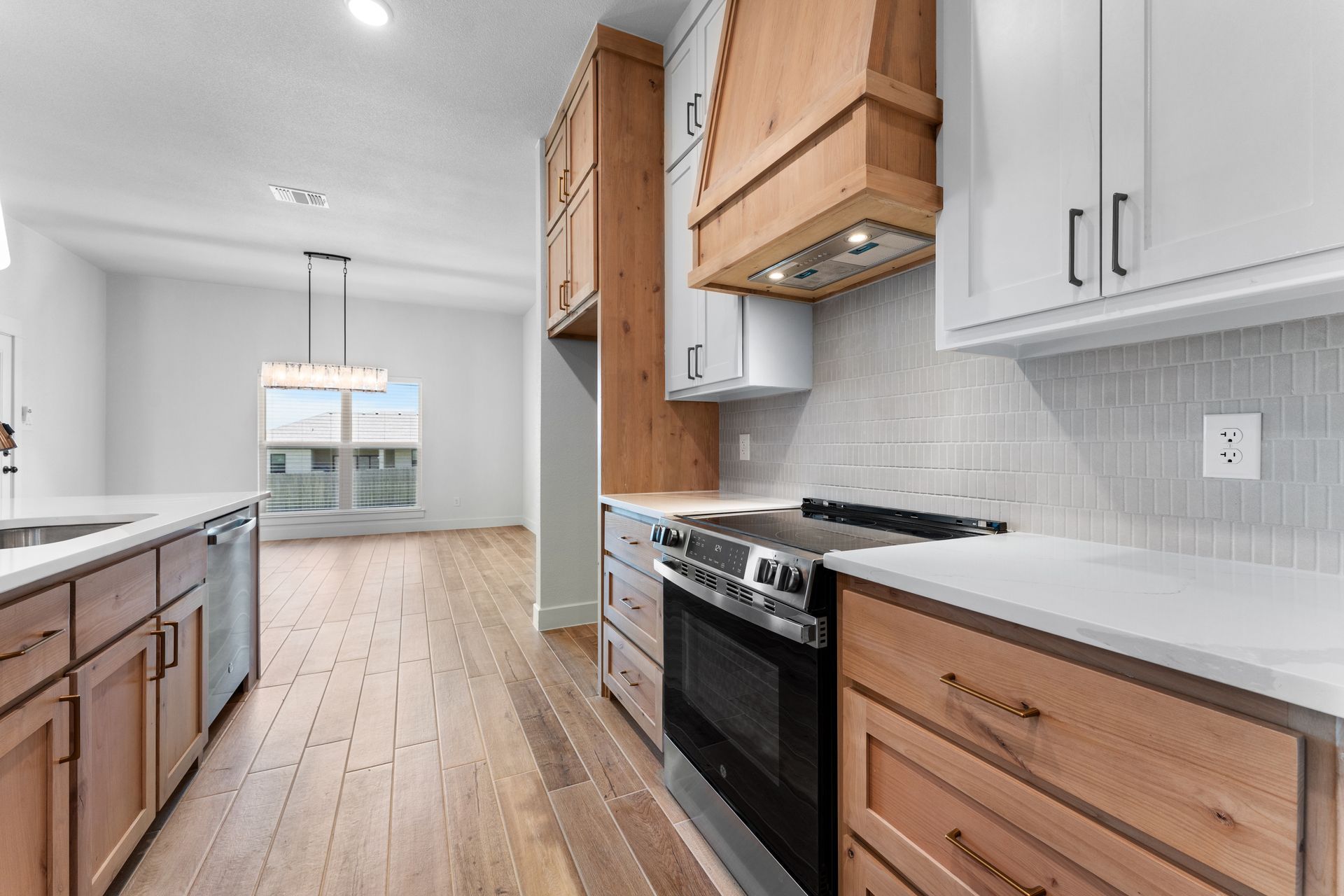 Modern kitchen with white and wood cabinets, stainless steel appliances, and wood flooring.