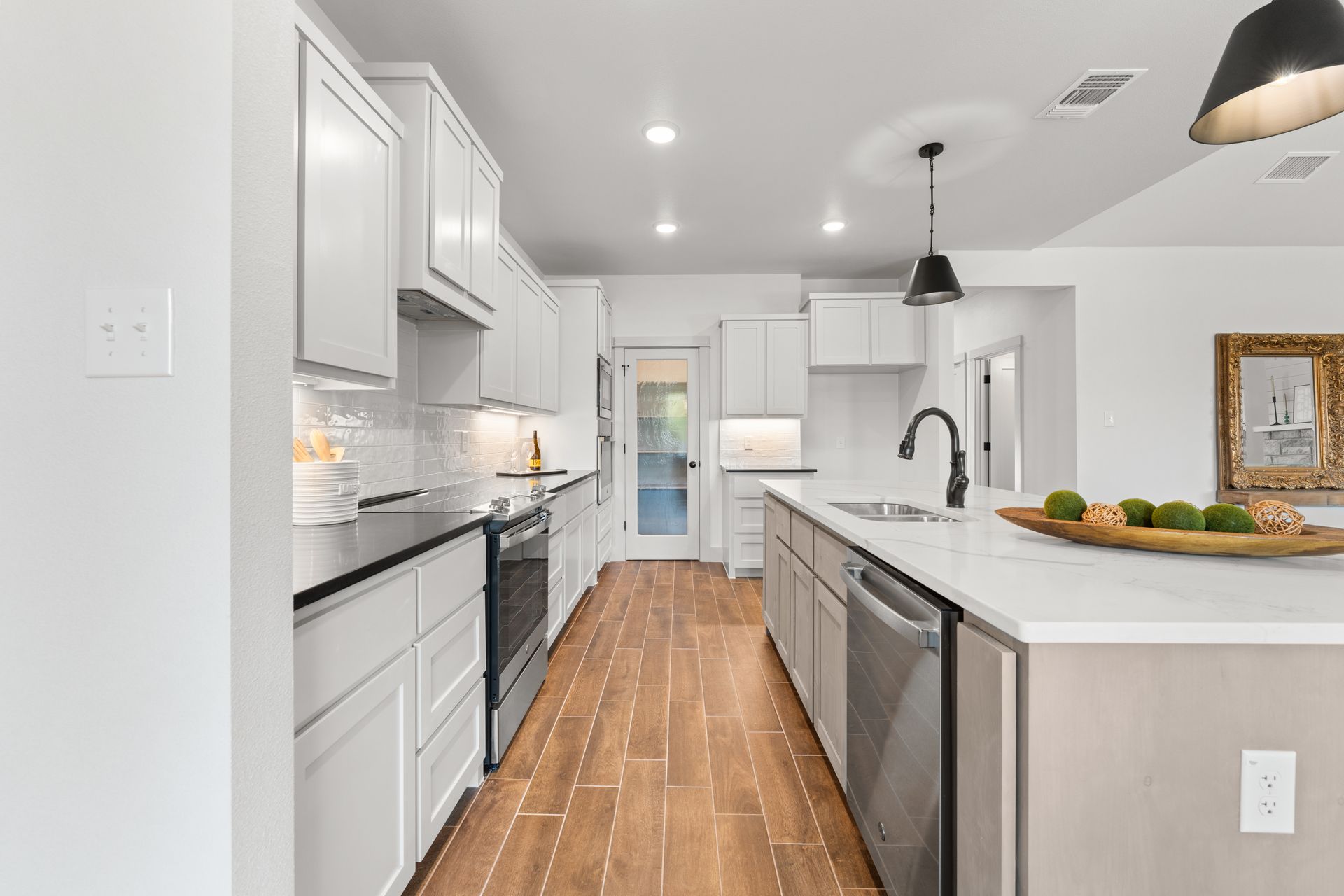 White kitchen with wood floors, stainless steel appliances, and white cabinets.