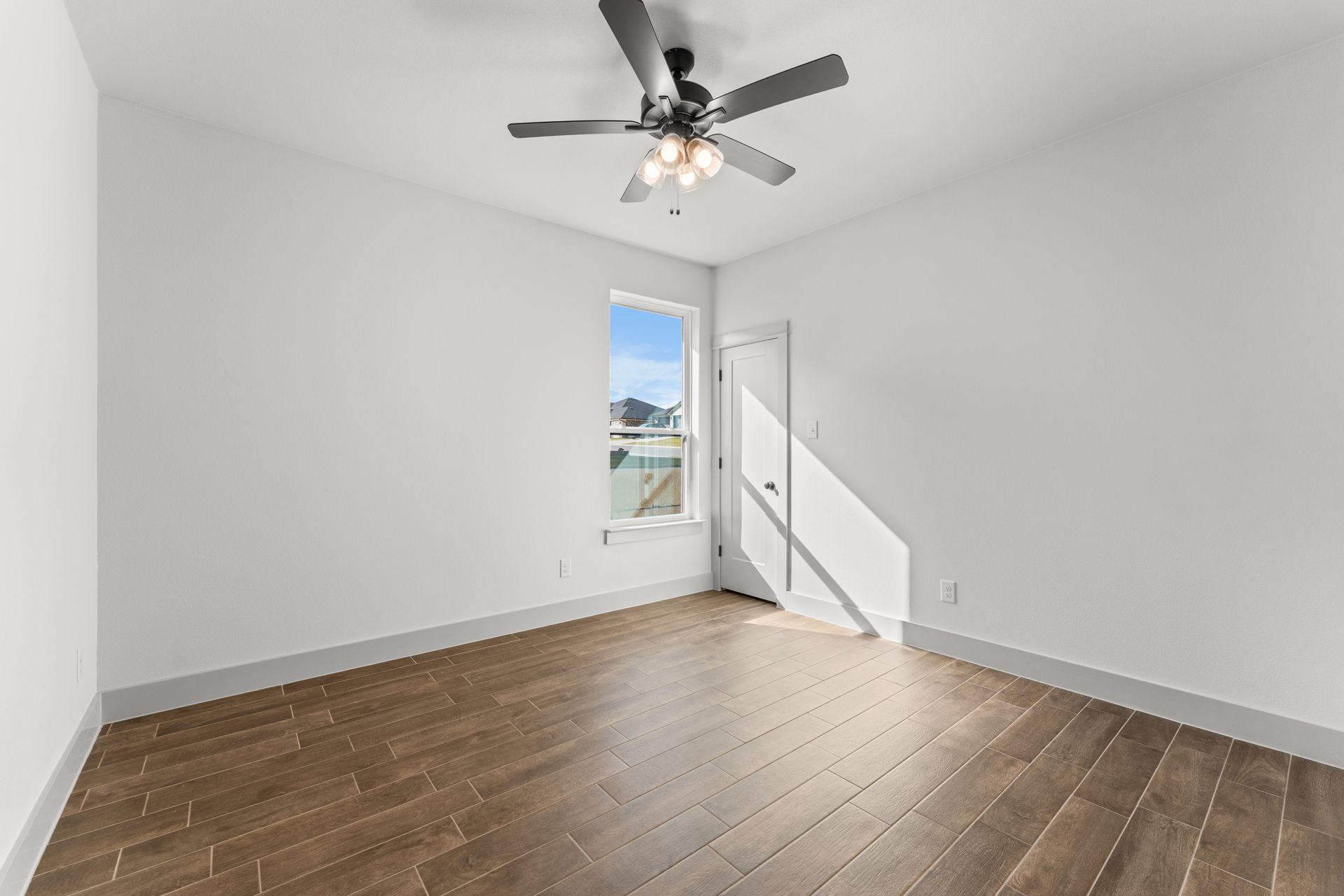 Empty room with hardwood floors, a window, and a ceiling fan.