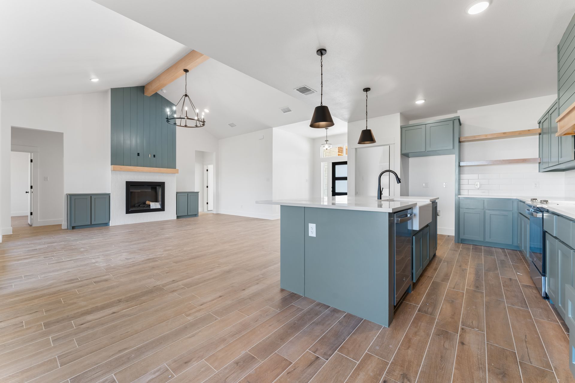 Open-concept kitchen and living area with blue cabinets, wood floors, and fireplace.