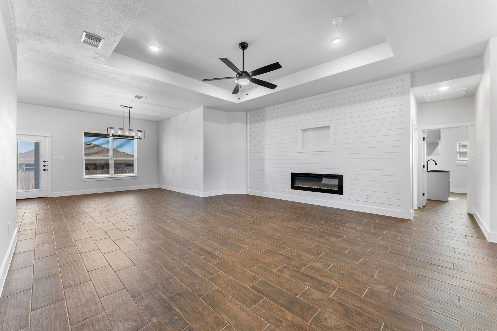 Empty, modern living room with wood floors, white walls, and a fireplace.