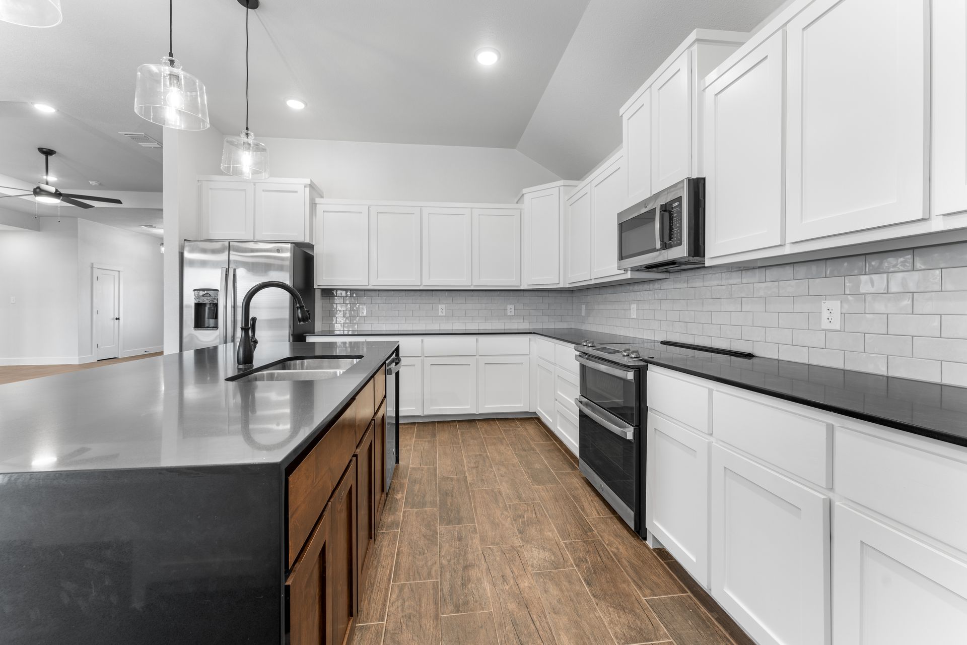 Modern kitchen with white cabinets, dark countertops, and a wooden island.
