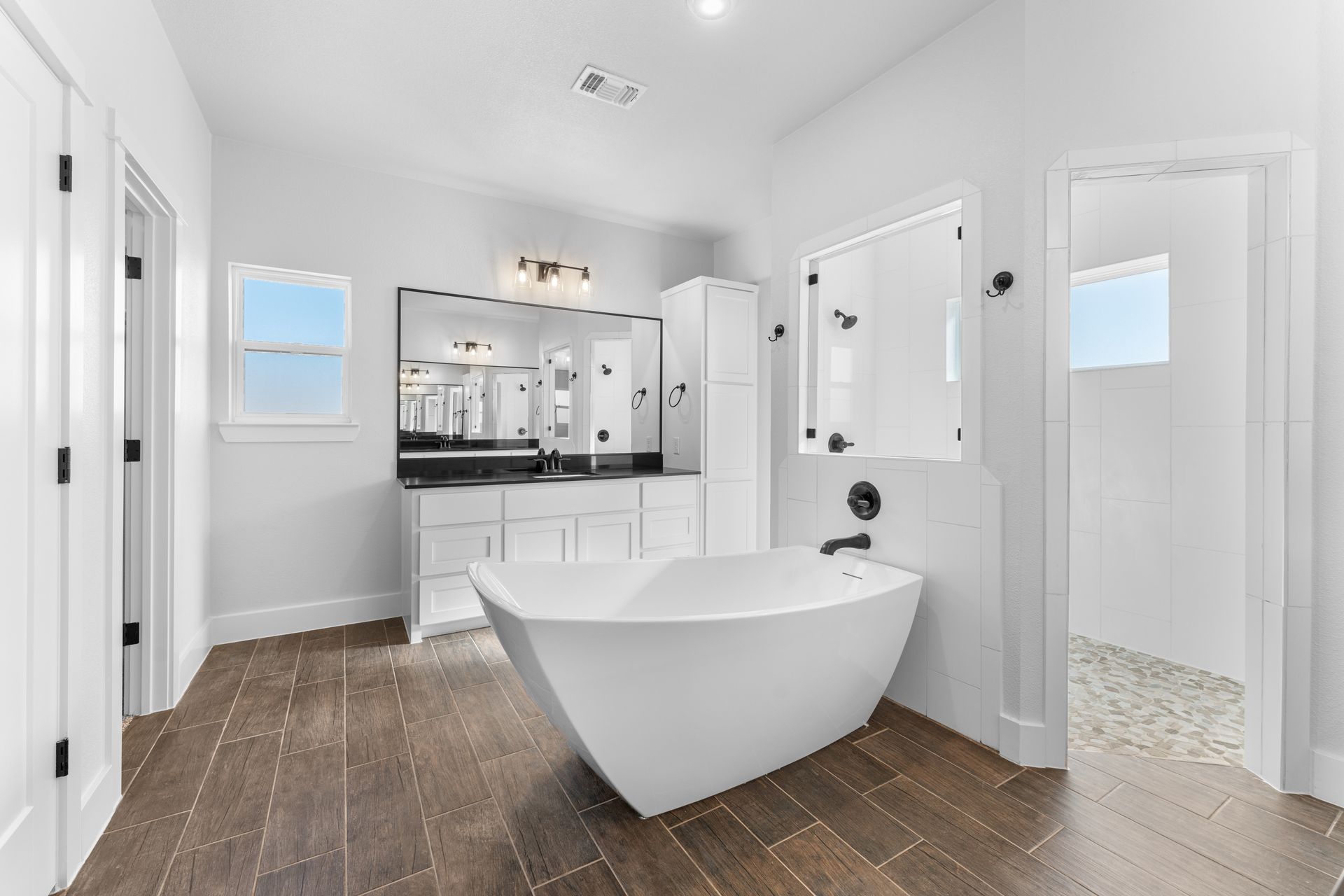 Modern white bathroom with a freestanding tub, double vanity, and separate shower.