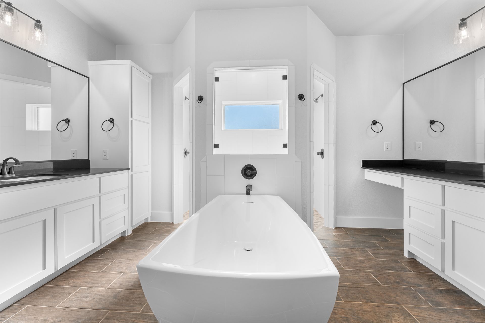 Bright white bathroom with a freestanding tub, dual vanities, and a central mirror.