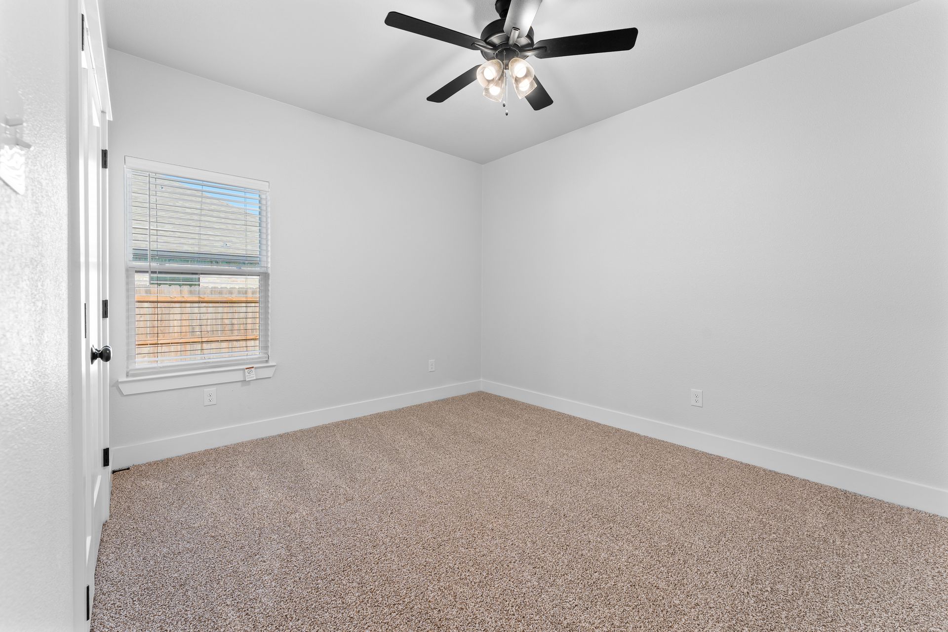 Empty room with beige carpet, white walls, a window, and a ceiling fan.