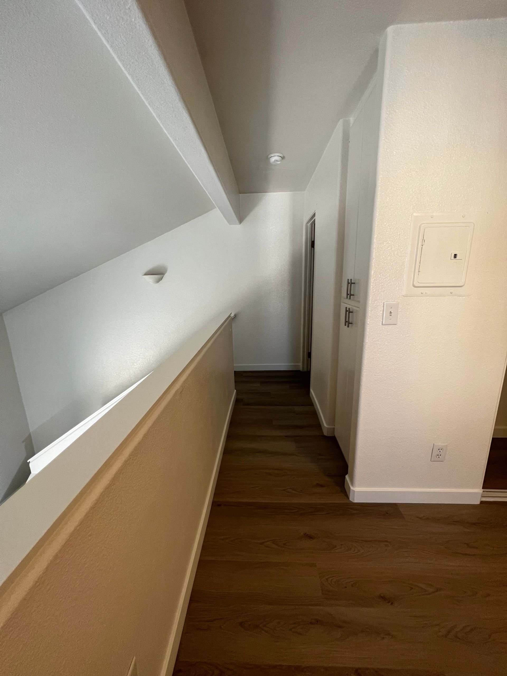 A long hallway with hardwood floors and white walls in a house.