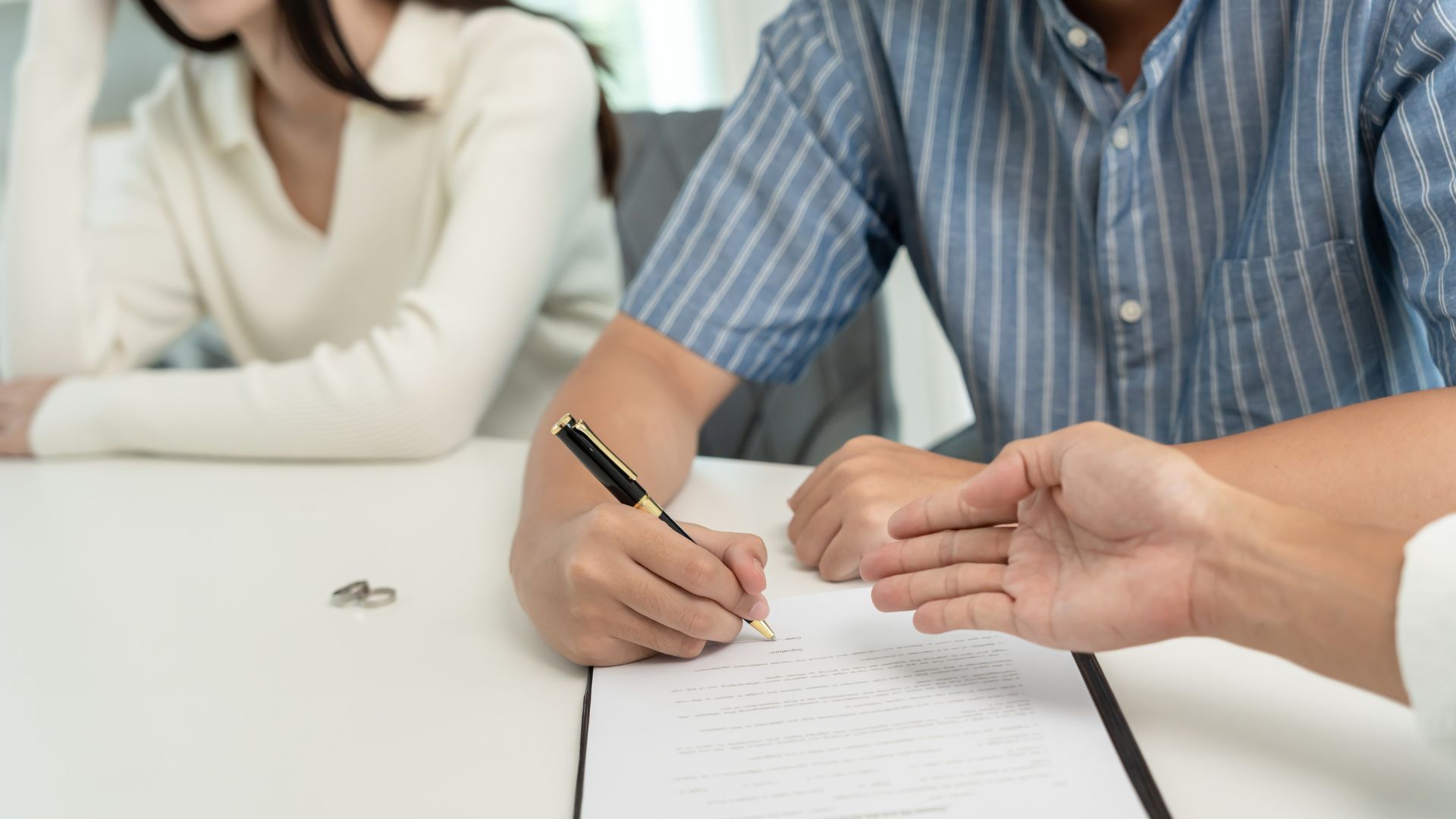 Two people signing a document at a desk during a meeting