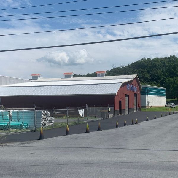 Red and white commercial building, dark asphalt road, blue sky, mountain in the background.