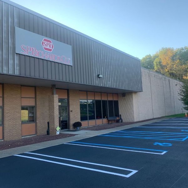 Exterior of a commercial building with parking spaces. Sign reads