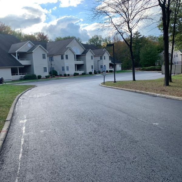 Paved road curves past multi-story apartment buildings under a partly cloudy sky.