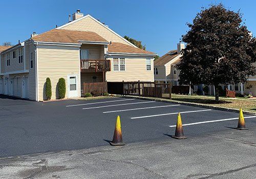 Apartment complex with freshly paved parking lot and traffic cones.