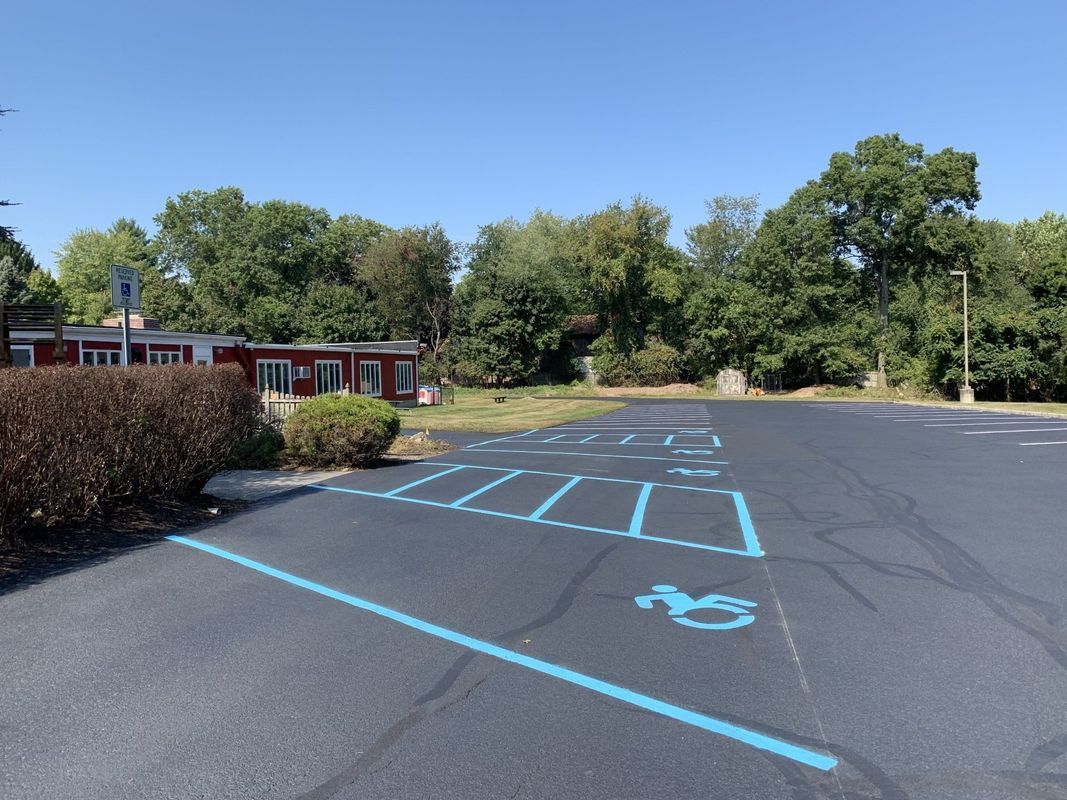 Parking lot with blue painted handicap symbols and parking lines. A building is in the background.