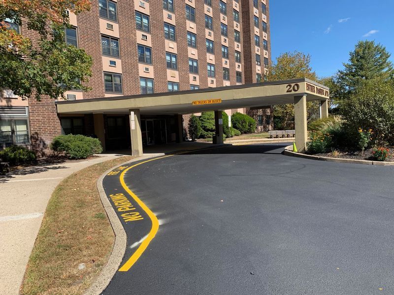 Entrance of a brick apartment building with a covered drive-up area, blue sky.