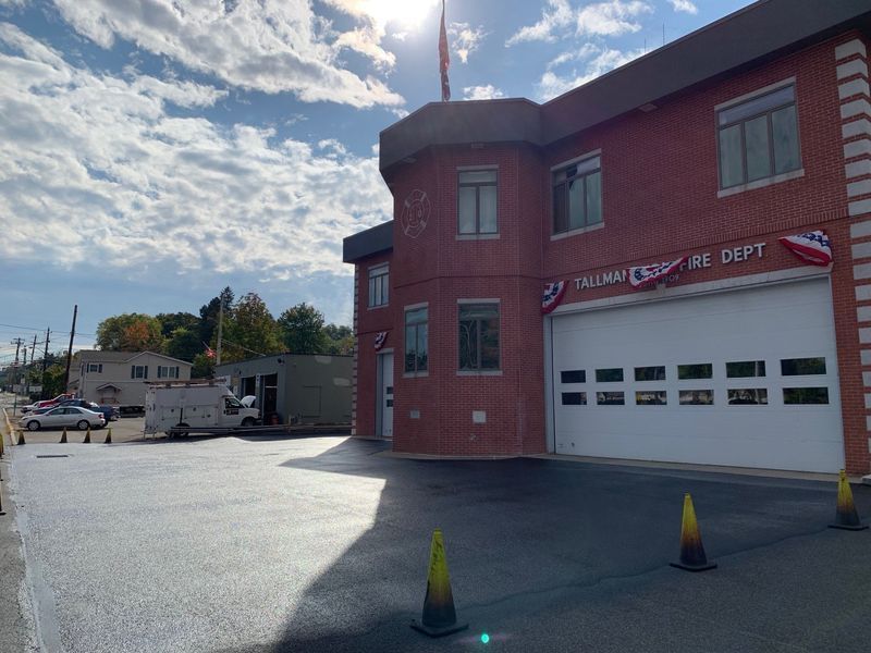 Red brick fire station with a closed white garage door under a blue sky.