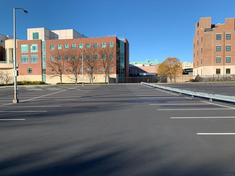 Empty parking lot with buildings in the background on a sunny day.