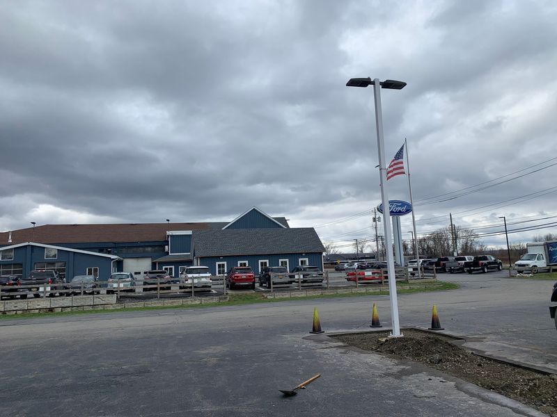 Ford dealership with American flag; cloudy sky.