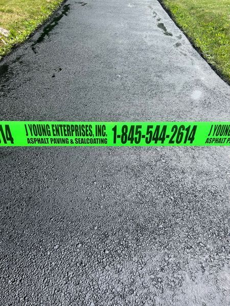 Newly paved asphalt path with green warning tape from I Young Enterprises.