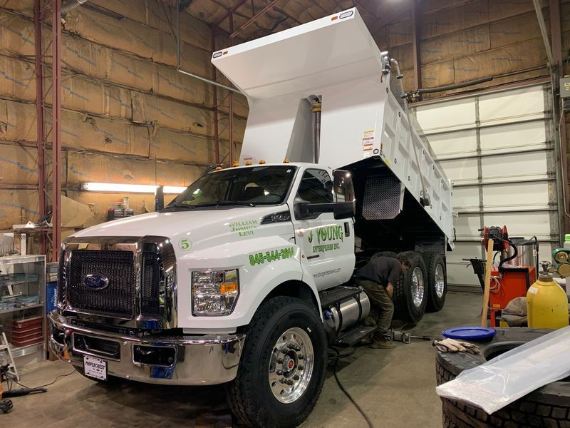 White dump truck with raised bed in a garage.